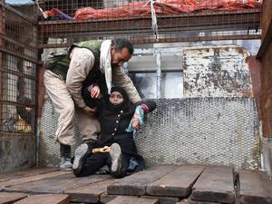 A wounded Syrian woman from the al-Sukari neighborhood is helped onto the back of a truck as she flees during the ongoing government forces military operation to retake remaining rebel-held areas in Aleppo on December 14, 2016. (AFP/George Ourfalian)