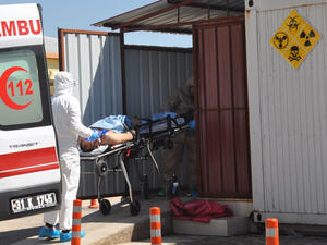 An injured Syrian is taken from an ambulance in Hatay province by Turkish officials wearing protective clothing, 4 April 2017. (AFP/Dogan News Agency)