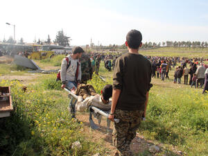 A wounded Syrian, evacuated from government-held Foua and Kefraya, is carried into a field after a car bomb targeted the buses carrying the evacuees. (AFP/Omar Haj Kadour)