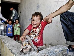 A Syrian man holds his infant in front of a disused house. (AFP)