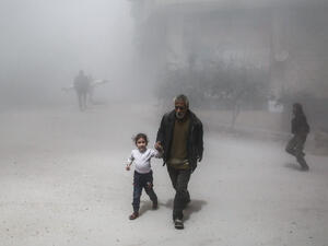 A Syrian man and girl flee following a reported government air strike on the rebel-controlled town of Hamouria. (AFP/ File Photo)