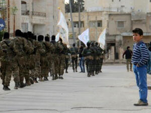 A Syrian boy looks at rebel fighters from the Jaish al-Fatah (or Army of Conquest) brigades marching through the northwestern city of Idlib in March 2017. (AFP)