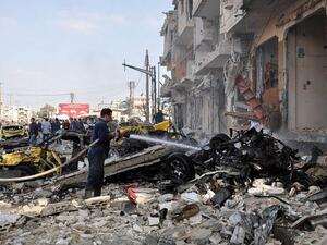 Syrian firefighters spray water on burning car at the site of a double car bomb attack. (AFP/Stringer)