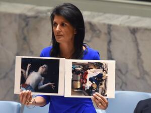 US Ambassador to the UN, Nikki Haley holds photos of victims as she speaks as the UN Security Council meets in an emergency session at the UN on April 5, 2017, about the suspected deadly chemical attack that killed civilians, including children, in Syria. (AFP/Timothy A. Clary)
