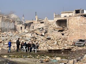 Syrians sit in the street on front of a destroyed building in Aleppo's old city on January 19, 2017, a month after government forces retook the northern Syrian city from rebel fighters. (AFP/George Ourfalian)