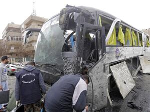 Syrian forensics examine a damaged bus at the scene of a bombing following twin attacks targeting Shiite pilgrims in Damascus' Old City on March 11, 2017. (AFP/Louai Beshara)