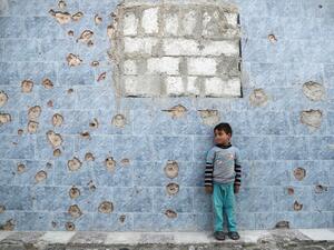 A Syrian boy stands against a bullet-riddled wall in the rebel-held town of Douma, on the eastern outskirts of the Syrian capital Damascus, on April 24, 2017. (AFP/Abd Doumany)