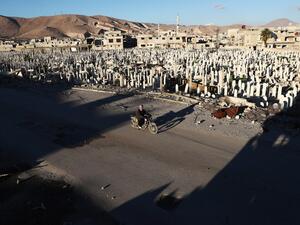 A Syrian man rides a motorbike past a cemetery in the rebel-held town of Douma, on the eastern outskirts of Damascus, on January 3, 2017. (AFP/Abd Doumany)