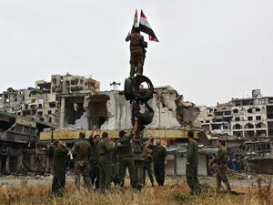 Syrian government fighters raise the country's flag after a previous evacuation of opposition fighters in 2014. (AFP)  
