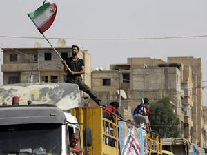 A Syrian man holds the Iranian flag as a convoy carrying aid provided by Iran arrives in the eastern city of Deir Ezzor. (LOUAI BESHARA/ AFP)