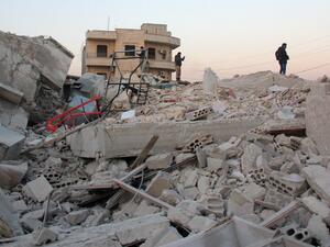 Syrian men stand amidst the rubble of a building following a reported airstrike by government forces, in the Syrian town of Binnish, on the outskirts of Idlib, on January 12, 2017. (AFP/Omar Haj Kadour)