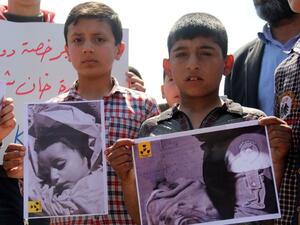 Syrian residents of Khan Sheikhoun hold placards and pictures on April 7, 2017 during a protest condemning a suspected chemical weapons attack on their town that killed at least 86 people, among them 30 children. (AFP/Omar Haj Kadour)