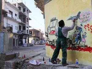 Syrian artist Aziz al-Asmar works on a mural depicting the war in Syria. (AFP/File)