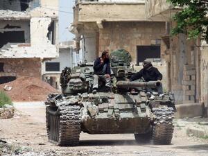 Syrians ride on the turret of a moving tank in the rebel-held area of Daraa, in southern Syria, on April 12, 2017. (AFP/Mohamad Abazeed)