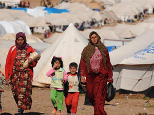 Syrian internally displaced people walk in the Atme camp, along the Turkish border in the northwestern Syrian province of Idlib. (AFP/ File)