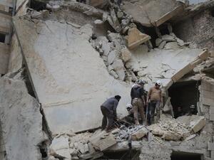 Syrian men and Civil Defence volunteers, also known as the White Helmets, search for survivors amid the rubble of a building following an air strike on the village of Maaret al-Numan, in the country's northern province of Idlib, on January 7, 2017. (AFP/Mohamed al-Bakour)
