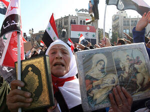 A Syrian woman holds up a copy of the Muslim holy Quran next to a Christian icons, during a demonstration in the capital Damascus on November 28, 2011. (AFP/File)