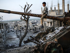 A boy sits on top of a destroyed tank in Syria, AFP/File