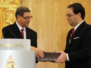 Tunisia's new Prime Minister Youssef Chahed and outgoing PM Habib Essid exchange documents during the handing-over ceremony in Carthage on August 29, 2016. (AFP/Stringer)