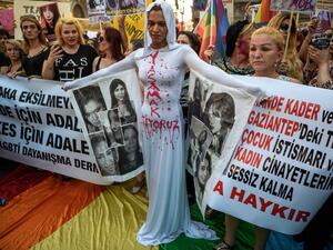 A LGBT protester stands in front of a banner and "We want to live" written on her body on August 21, 2016 in Istanbul during a demonstration against the murder of transgender activist Hande Kader.. (AFP/Ozan Kose)