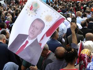 A man holds a flag with the portrait of Turkey President Recep Tayyip Erdogan as people gather during a meeting marking the 15th anniversary of the foundation of Justice and Development (AK) Party in Ankara, on August 14, 2016. (AFP/Adem Altan)