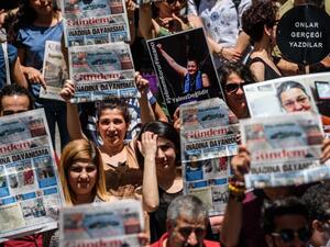 Protesters hold pictures of jailed RSF representative Erol Onderoglu, journalist Ahmet Nesin and rights activist and academic Sebnem Korur Fincanci as they shout slogans in front of the Pro Kurdish Ozgur Gundem newspaper's headquarters on June 21,2016 in Istanbul. (AFP/Ozan Kose)