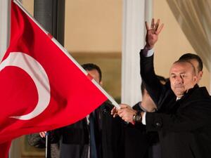 Turkish Foreign Minister Mevlut Cavusoglu waves a Turkish flag as he arrives at the residence of Turkey's consul general in Hamburg, northern Germany, on March 7, 2017. (AFP/Daniel Reinhardt)