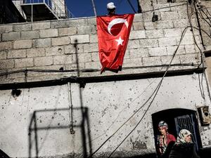 A man hangs a Turkish flag in the border town of Kilis, after Daesh rockets struck the town. (AFP/Yasin Akgul)