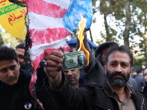 An Iranian protester burns a dollar banknote during a demonstration outside the former US embassy in the Iranian capital Tehran on November 4, 2018. (ATTA KENARE / AFP)