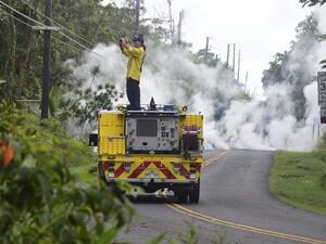 A firefighter takes photos near steam rising from a fissure in Leilani Estates subdivision on Hawaii's Big Island on May 4, 2018. (FREDERIC J. BROWN / AFP)