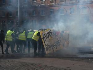 Protesters hide behind a banner amid tear gas smoke during a demonstration in Toulouse, southern France, on February 9, 2019. (AFP/ File)