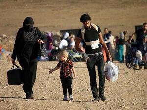 Syrians walk carrying their belongings after crossing the Syria-Jordan border. (AFP)
