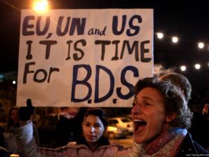 Demonstrators hold a placard urging the international community to support the Boycott, Divestment, and Sanctions (BDS) campaign. (AFP/ File Photo)