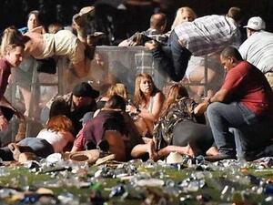LAS VEGAS: People roll over a wall in a scramble for shelter after a gunman opened fire on an open-air music festival in Las Vegas, killing at least 58 and injuring over 500. (AFP)  