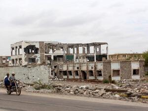 Yemeni ride past a damaged building outside of Aden. After a year of fighting, the destruction is widespread. (AFP/Saleh al-Obeidi)