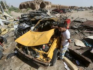 An Iraqi man stands next to the wreckage of cars in the aftermath of a massive suicide car bomb attack. (AFP)