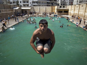 Men, women, children and even the elderly are taking swimming lessons at Jordanian sports clubs. Photo of Syrian child swimming in Aleppo. (AFP/File)