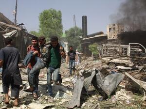 Syrian men help an injured person after a reported barrel bomb attack by Syrian government forces hit an open market in the northern city of Aleppo, on June 3, 2015, killing and injuring people. (AFP/Karam al-Masri)