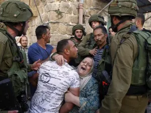 A Palestinian woman tries to prevent the arrest of a Palestinian man by Israeli soldiers in the southern occupied West Bank city of al-Khalil (Hebron) on September 20, 2016. (AFP)
