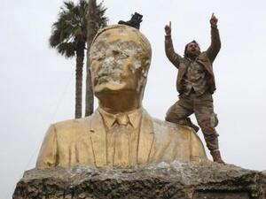 A militant from the Army of Conquest alliance destroys a statue of Bashar al-Assad in Syria's Idlib Province. (Al Bawaba/File)