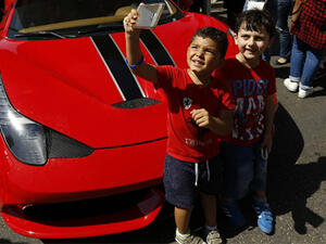 Two children pose for a picture next to a Ferrari during the 2016 Beirut Grand Prix, a Supercar racing event for non-professional drivers, in the capital's Ramlet al-Baida neighberhood.(AFP/File)