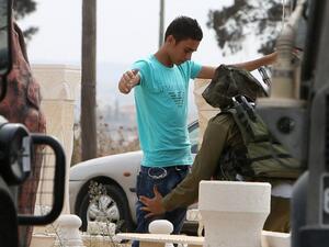 An Israeli soldier checks a Palestinian youth near the Jalama checkpoint, where a Palestinian man allegedly carried out a stabbing attack earlier. (AFP/File)