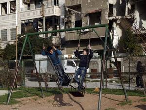 Syrian children play on a swing at a park in the rebel-held town of Douma, on the eastern edges of the capital Damascus on February 27, 2016, on the first day of the landmark ceasefire agreement. (AFP/Samir al-Doumy)