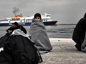 Children wrapped in covers stand in a harbour as migrants and refugees arrive on the Greek island of Lesbos while crossing the Aegean Sea from Turkey on March 2, 2016, in Mytilene. (AFP/File)