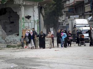 Families walk through bombed-out buildings in Daraa, Syria. (AFP/File)