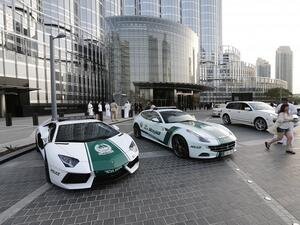 A picture taken on April 25, 2013 shows a Lamborghini (L) and Ferrari police vehicles at the foot of the Burj Khalifa tower in Dubai. (AFP/ Karim Sahib)