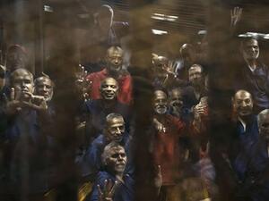 Egyptian Muslim Brotherhood defendants stand behind the bars during their trial. (AFP/File)