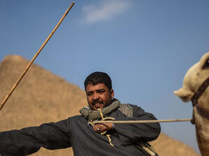An Egyptian man rides a camel in front of one the Giza pyramids in the southern Cairo Giza distri. (AFP/file)