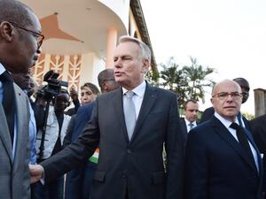 French Minister of Foreign Affairs Jean-Marc Ayrault (C) and French Interior Minister Bernard Cazeneuve (R) walk in front of one of the sites of the March 12 attack that killed 18 people in Grand Bassam. 