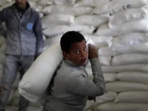 طفل فلسطيني يحمل كيس طحين في مركز توزيع اعانات الانروا/أ.ف.ب